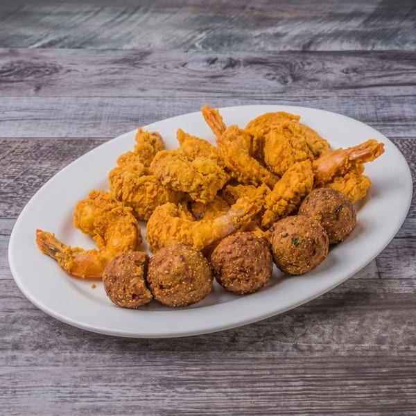 Golden fried shrimp and hush puppies served on a white oval plate.